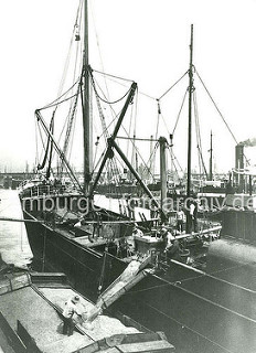 Alte Fotografie, Hafenarbeit im Hamburger Hafen - die Ladung eines Getreidefrachters wird gelöscht; die Schiffswinde bringt das Getreide in Körben hoch, über eine Schüttrinne wird es in einen offenen Kahn transportiert.