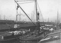 Melniker Ufer im Moldauhafen; Hafenbecken im Hamburger Hafen - eine Dampfwindenschute verlädt Korn in Säcken von einem Oberländer Kahn auf eine Kastenschute.