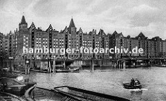 Blick über den Brooktorhafen zu den Speicherblöcken V + X. Schuten und Kähne liegen an der Kaimauer oder den Holz Duckdalben. Eine kleine Barkasse fährt durch das Hamburger Hafenbecken Richtung Magdeburger Hafen.