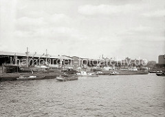 Blick zum Dalmannkai des Grasbrookhafens, der 1881 parallel zum Sandtorhafen verlaufend fertig gestellt wurde. Die Ladung der Frachtschiffe wird über die Hafenkrane gelöscht oder die Frachter werden neu beladen.