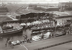 Luftfoto vom Rosshafen im Hamburger Hafen; Frachtschiffe liegen an den Dalben. Die Ladung eines der Frachter wird über Binnenschiffe und Kähne, die längseits fest gemacht haben gelöscht. Links im Hintergrund Helgen der Howaldtswerft und im Hi