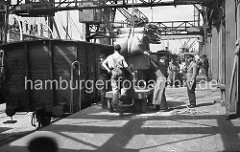 Arbeit im Hamburger Hafen ca. 1948; ein Frachter wird im Roßhafen gelöscht. Der Kran bringt die Säcke aus dem Laderaum des Schiffs an Land - Kaiarbeiter nehmen die Ladung in Empfang. Auf einem Elektrokarren werden die Säcke in den Lagerschuppen geb