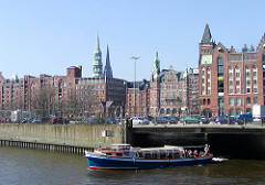 Eine Barkasse kommt vom Brooksfleet und fährt in den Brooktorhafen ein - am Ufer der Zollzaun des Hamburger Freihafens.