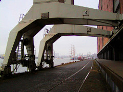 Alte Ansicht von den Portalkränen beim Kaispeicher A an der Elbe in der Hamburger Hafencity. Im Hintergrund Segelschiffe bei den Landungsbrücken.