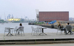 Terrasse mit Stühlen am Grasbrookhafen - im Hintergrund der Kaispeicher A und die Norderelbe. ( 2004 )