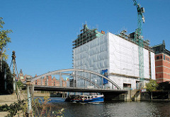Bauarbeiten am Kaispeicher B - Umbau zum Maritimen Museum - eine Barkasse fährt durch das Hafenbecken Richtung Elbe.