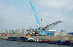 Ein Kran mit Greifer löscht die Ladung eines Binnenschiffs am Kirchenpauerkai im Hamburger Hafen.