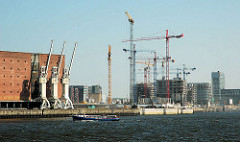 Blick über die Norderelbe zum Grasbrookhafen - Baustellen für Neubauten, Baukräne am Dalmannkai; lks. die Kräne vor dem Kaispeicher A, der zukünftigen Elbphilharmonie Hamburgs.