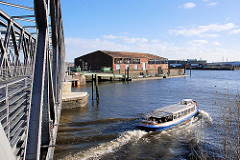 Eine Barkasse kommt aus dem Magdeburger Hafen und fährt Richtung Norderelbe - lks. ein Lagergebäude am Versmannkai / Bueno Aires Kai und die Einfahrt zum Baakenhafen.