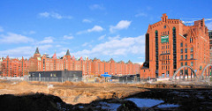Baustelle am Überseequartier bei der Dalmannstraße in der Hamburger Hafencity; Blick zur Magdeburger Brücke und dem Kaispeicher B am Magdeburger Hafen - im Hintergrund  die Lagerhäuser der Speicherstadt.