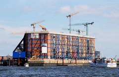 Baustelle der Hamburger Elbphilharmonie - der Kaispeicher ist eingerüstet. Sportboot und Ausflugsboot mit Touristen auf der Norderelbe.