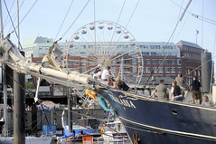 Fotos vom Hamburger Hafengeburtstag - Hochbetrieb auf dem Wasser und an Land; Schiffsbug / Bugsprit der Thalassa vor den Landungsbrücken, im Hintergrund ein Riesenrad.