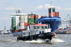 Fotos vom Hamburger Hafengeburtstag - Hochbetrieb auf dem Wasser und an Land; Lotschiff Lotse 2 in Fahrt - dahinter ein hoch beladener Containerfeeder.