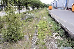 Stilgelegte Schienen / Gleise der Hafenbahn an der Versmannstraße in der Hamburger Hafencity - Lagergebäude mit Rampe, lks. die Zollstation / Zollübergang.