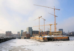 Baustelle vom Spiegelgebäude an der Ericusspitze in der Hamburger Hafencity - Baukräne am Bauplatz; lks. der Ericusgraben - re. der Zollkanal.