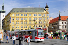 Historische Architektur auf dem Freiheitsplatz / Namesti Svobody in Brno / Brünn - eine rote Strassenbahn steht an einer Haltestelle - lks. der Kirchturm der spätgotischen St. Jakobskirche, re. die Mariensäule, Pestsäule.