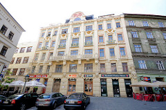 Jugenstilhaus in Brno - Jugenstilfassade Etagenhaus in Brünn - Geschäfte im Erdgeschoss, parkende Autos.