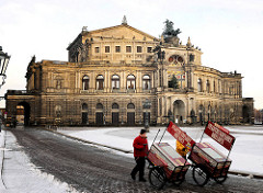 Historische Architektur Dresdens - Semperoper am Theaterplatz; zweirädrige Karren der Dresdner Stadtrundfahrt werden durch den Schnee zum Arbeitsplatz geschoben.