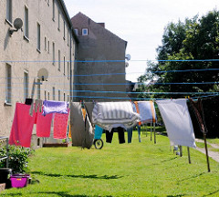 Wäsche trocknen in der Sonne auf der Wiese / Hinterhof mehrstöckiger grobverputzter Wohnblock.