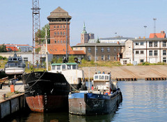 Frachtschiffe am Kai im Straslunder Hafen - im Hintergrund Gewerbegebäude und ein historischer Speicher.