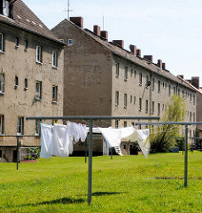 Wäsche trocknen in der Sonne auf der Wiese / Hinterhof mehrstöckiger grobverputzter Wohnblock.