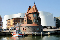 Altes Lotsenhaus im Stralsunder Hafen, dahinter die weisse Architektur des Ozeaneum Stralsund. Der Entwurf für das Meeresmuseum stammt von den Architekten Elke Reichel und Peter Schlaier des Stuttgarter Architekturbüros Behnisch, Behnisch & Partner.