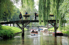 Brücke über eine Gracht in Friedrichstadt - grüne Zweigen von Weiden hängen tief über das Wasser.