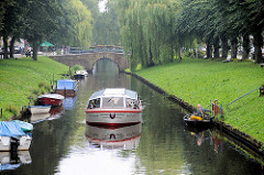 Fahrgastschiff mit geschlossenem Verdeck in einer Gracht von Friedrichstadt - Sportboote am Ufer des Kanals.