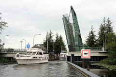 Die Klappbrücke an der Schleuse des Giselaukanals ist geöffnet, ein Sportboot hat die Schleuse verlassen.