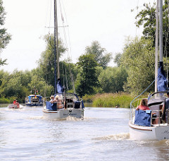 Sportboote in Fahrt auf der Krückau - Segelboote unter Motor und Motorboote.
