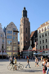 Blick über den Marktplatz von Wroclaw / Beslau; Touristen und Spaziergänger in der Sonne - im Hinergrund historische Architektur / Hausfassaden und der Kirchturm der St. Elisabeth Kirche - gotischer Kirchenbau, Backstein Anfang des 14. Jahrhunderts -