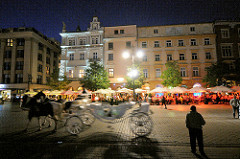Abend in Krakau - Pferdekutsche; Restaurants unter Sonnenschirmen auf dem Hauptmarkt in Krakau.