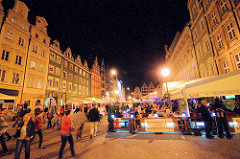 Nachtaufnahme Grosser Ring, Rynek in Wroclaw / Breslau - Touristen gehen am Abend über den Marktplatz oder sitzen im Freien in Restaurants unter Markisen.