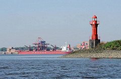 Leuchtfeuer auf der Elbinsel Pagensand - Einfahrt zur Pagensander Nebenelbe. Im Hintergrund Kaianlagen, Hafenanlagen und Frachtschiff auf der gegenüber liegenden Seite der Elbe in Bützfleth.