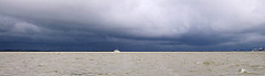 Gewitterwolken über der Elbe bei der Mündung der Stör - dunkle Wolken liegen dicht über dem Wasser; ein Sportboot wird von der Sonne angestrahlt.
