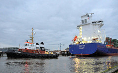 Der Containerfeeder EMOTION  fährt am frühen Morgen mit Hilfe eines Schleppers in die Schleusenkammer der Brunsbüttler Schleuse des Nord-Ostsee-Kanals ein.
