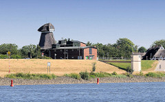 Elbdeich mit ehem. Mühle in Hamburg Altengamme - am Elbufer rote Fahrwassertonnen  am rechten Flussufer; gelbes Kreuz markiert den Übergang der Fahrtrinne zur anderen Seite der Elbe.
