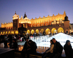 Nachtaufnahme Marktplatz von Krakau - beleuchteter Springbrunnen; im Hintergrund die angestrahlten Tuchhallen - Renaissancearchitektur, erbaut Ende des 16. Jahrhunderts.