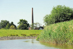 Schilf am Ufer der Krückau - Fabrikschornstein zwischen Hausdächern.
