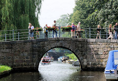 Gracht mit schmaler Brücke in Friedrichstadt - Touristen fotografieren die Stadt.