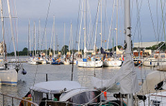 Sportboothafen Brunsbüttel neben der Schleuse - Segelboote und Motorboote liegen nebeneinander am Steg.
