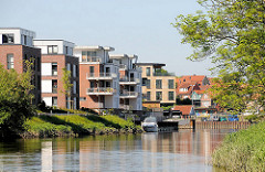Moderne Wohnungen am Ufer der Schwinge in Stade - Neubauten mit Balkon zum Wasser - Bootssteg mit Sportboot; im Hintergrund der Stader Hafen.