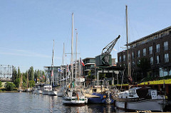 Sportboote im Stader Hafen - historischer Hafenkran und Wohnhäuser - lks. im Hintergrund das Gasometer, das als Industrieanlage unter Denkmalschutz steht.