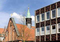 Dach und Glockenturm der Heiligen Geistkapelle in Uelzen - 1320 als Bestandteil des Heiligen Geist Hospitals erbaut. Rechts Fassade eines Geschäfsgebäude - Bürogbäudes, Achitekur der 1970er Jahre.