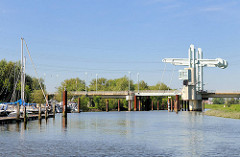 Blick über die Schwinge zur Klappbrücke der L111 / Buxtehuder Strasse; Sportboote am Ufer.