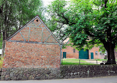 Fachwerkkate mit Ziegelsteinen - Steinmauer; im Hintergrund Gebäude eines Bauernhofs - Dorfstrasse Bünningstedt, Gemeinde Ammersbek.