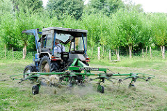 Heuernte auf einer Wiese in Bünningstedt / Ammersbek - ein Landwirt wendet mit seinem Traktor und dem Heuwender das gemähte Gras.