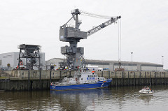 Hafen Glückstadt - Hafenkran an der Kaimauer - das Hamburger Polizeiboot HERBERT WEICHMANN hat an der Kaimauer festgemacht - ein Sportboot von der Elbe kommend läuft in den Glückstädter Hafen ein.