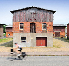 Fassade einer Scheune in Bünningstedt / Ammersbek - ein Teil der Fassade ist mit Holzbrettern verkleidet - ein Rennradfahrer auf der Strasse.