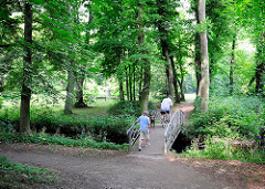 Spaziergänger auf einer Brücke im Glückstädter Stadtpark.
